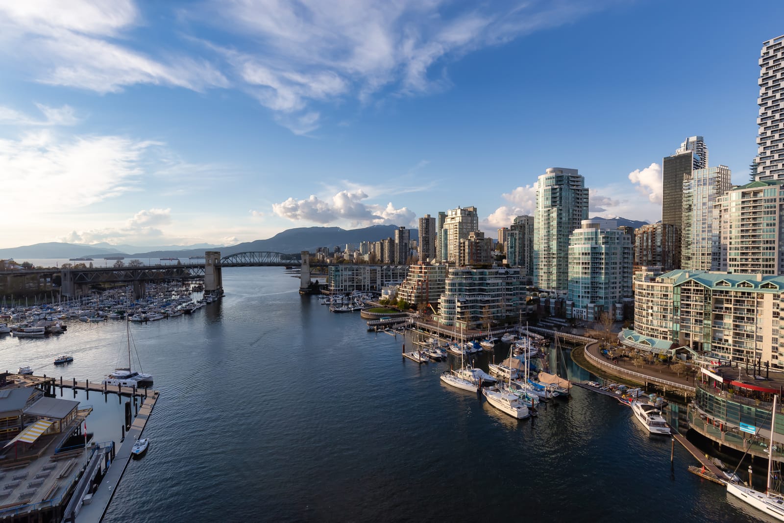 Marinas along False Creek below downtown Vancouver's glass towers, with mountains on the horizon